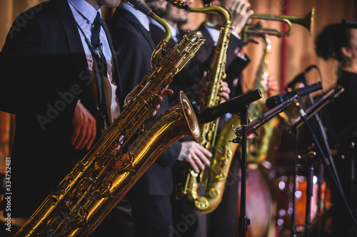 Concert view of a saxophonist, saxophone player with vocalist and musical during jazz band orchestra performing music on stage