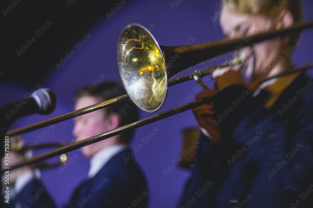 Fototapeta premium Concert view of a trombone player trombonist with musical jazz band performing in the background