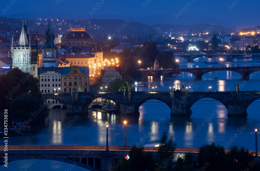 A distant view of historic buildings in Old Town from across the Vltava River at night. 
