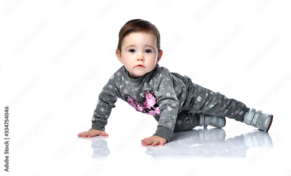 Toddler in gray suit with snowflakes print and boots. She is sitting on floor isolated on white studio background. Close up Toddler in gray suit with snowflakes print and boots. She is sitting on floor isolated on white studio background. Close up
