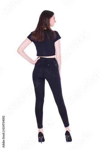 Back view portrait young beautiful brunette woman in black jeans