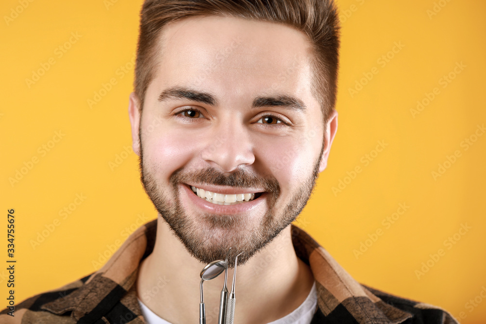 Obraz premium Happy smiling young man with dentist's tools on color background
