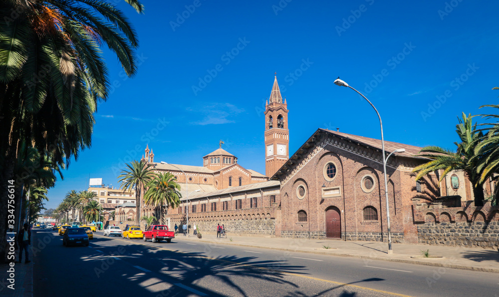 Obraz premium Asmara, Eritrea - November 01, 2019: Facade View to the Church of Our Lady of the Rosary and Palm Trees