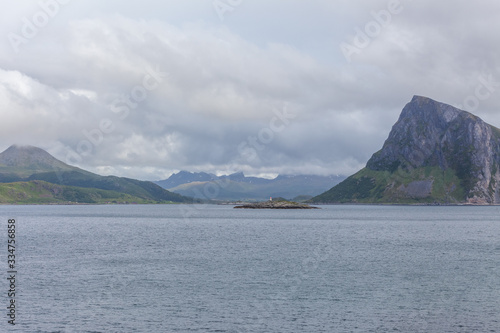 Norwegian fjord and mountains surrounded by clouds, ideal fjord reflection in clear water. selective focus. © Tatiana