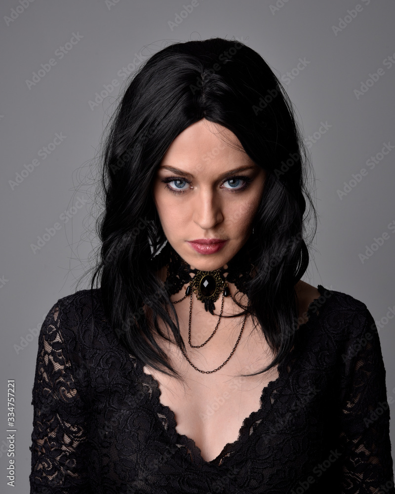 Close up portrait of a pretty, goth girl with dark hair posing in front a  studio background. Stock Photo