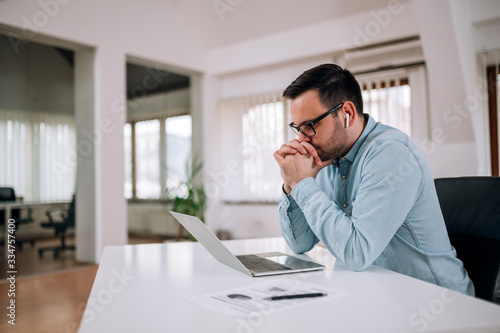 Worried entrepreneur looking at laptop screen at workplace, portrait.