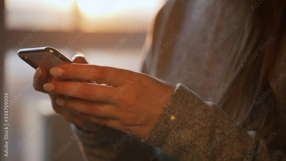 Female hands using smartphone against the setting sun. Female hands using smartphone against the setting sun.