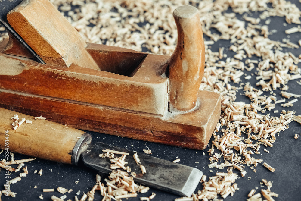 Old hand plane and chisel with wooden shavings on black background. Old woodworking hand tool. Copy, empty space for text Old hand plane and chisel with wooden shavings on black background. Old woodworking hand tool. Copy, empty space for text