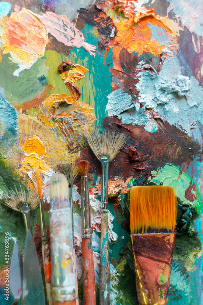 Fototapeta premium various brushes for oil paints are on the palette. set for the artist. multicolored background