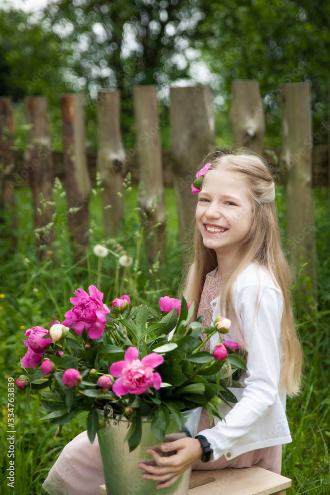 Beautiful little blonde girl with metal bucket with peonies