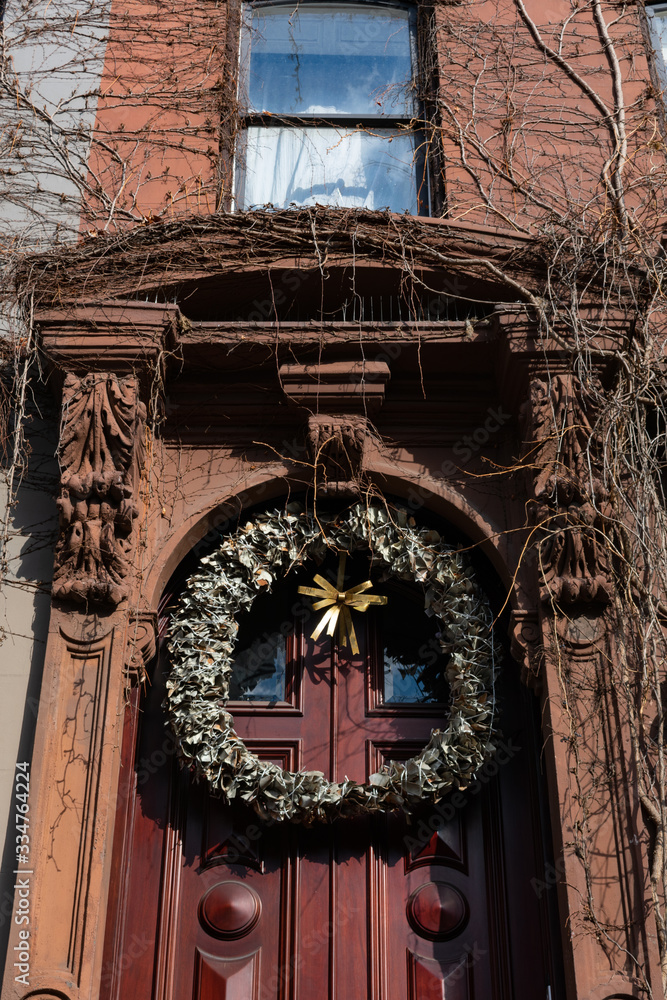 Fototapeta premium Christmas Wreath on the Entrance Door to an Old Brownstone Townhouse in New York City