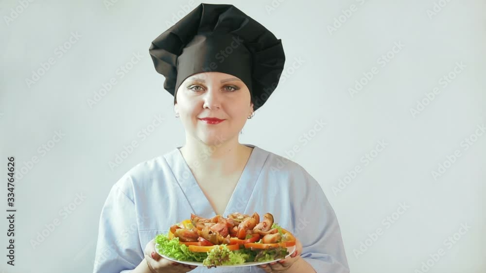 Female cook holding a plate with black tomato vegetable salad Female cook holding a plate with black tomato vegetable salad