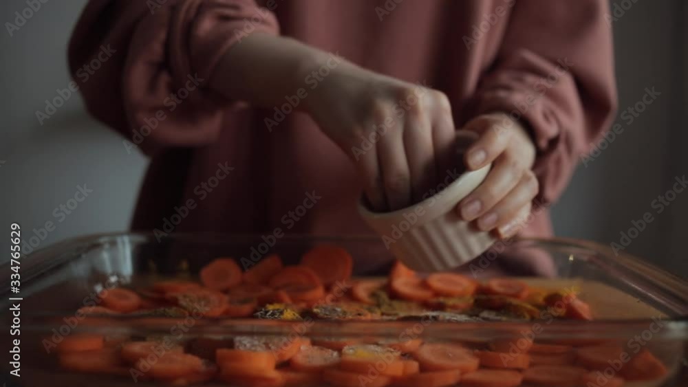 Hands of a young woman strew a dish with chopped carrots in her kitchen. Close-up Hands of a young woman strew a dish with chopped carrots in her kitchen. Close-up