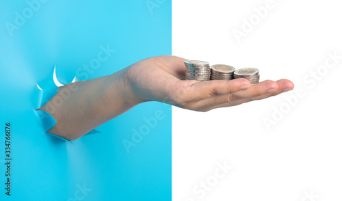 Hand holding coins through the torn blue plastic isolated on white background