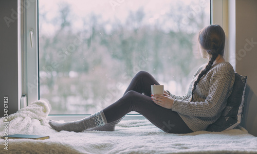 Woman with cup of coffee by the window