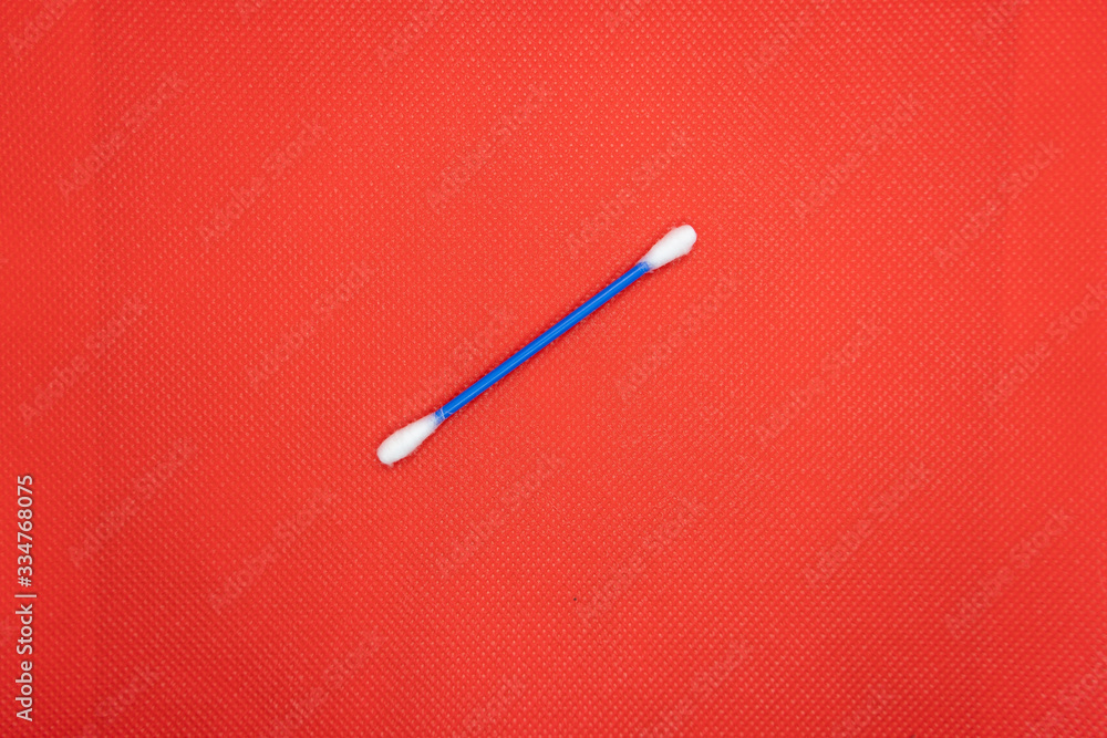 One white plastic ear stick with soft white cotton on the end. On a color textured background. Hygiene and ear cleaning products One white plastic ear stick with soft white cotton on the end. On a color textured background. Hygiene and ear cleaning products
