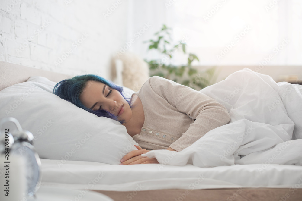 Selective focus of woman with colorful hair sleeping on bed in bedroom Selective focus of woman with colorful hair sleeping on bed in bedroom