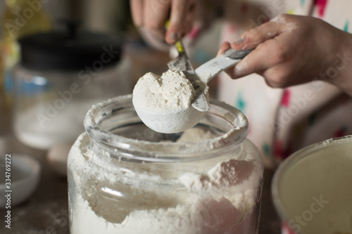 Картината върху платно close up of hands measuring flour with knife and measuring cup