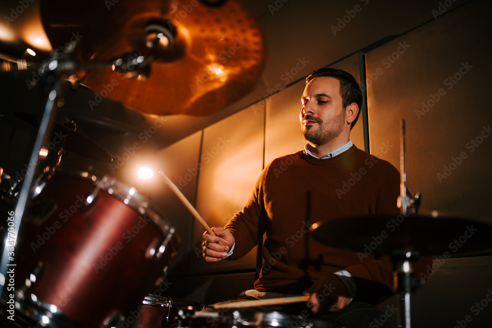 Naklejka premium Low angle image of a drummer playing indoors.