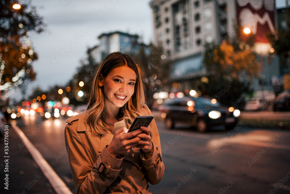 Beautiful woman using smart phone in the city, smiling at camera. Beautiful woman using smart phone in the city, smiling at camera.