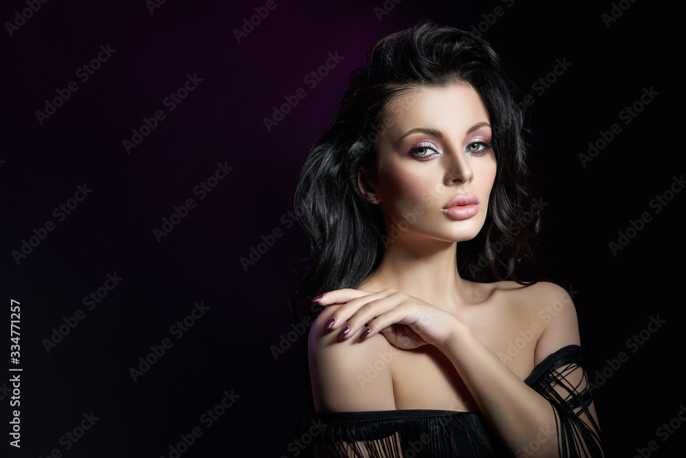 Portrait of a brunette woman with a chic, lush wavy hair, plump lips. Natural cosmetics and beautiful bright makeup on the face of the girl