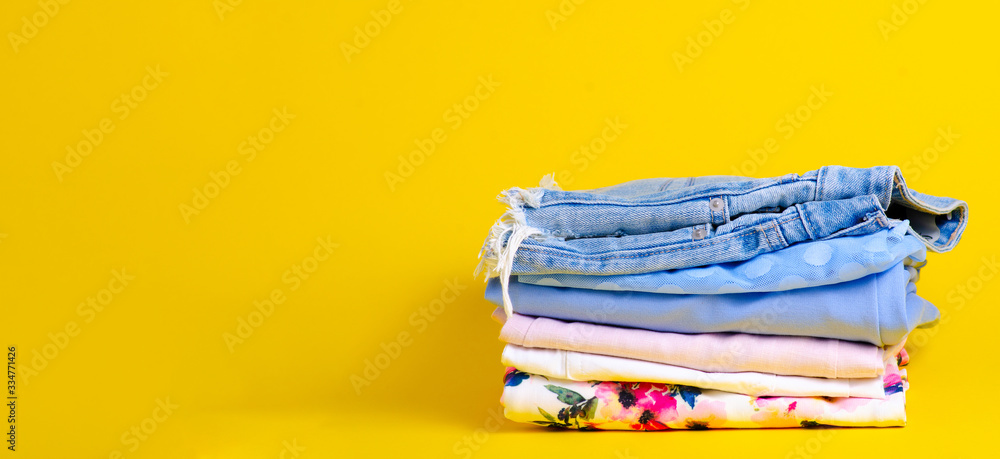 Stack folded colorful clothing summer on yellow background Stack folded colorful clothing summer on yellow background