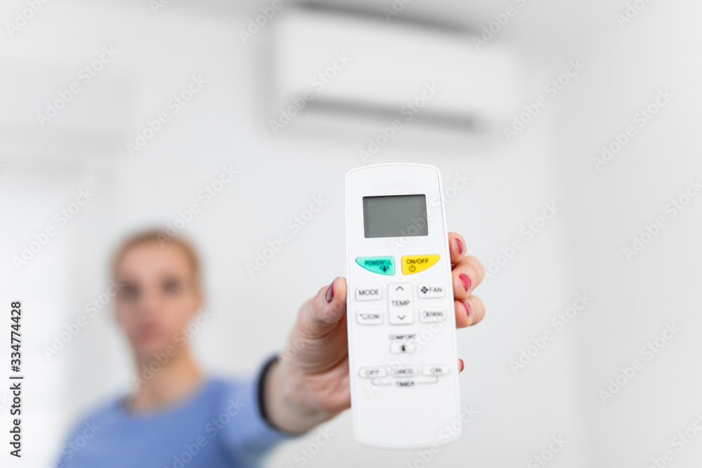 Woman holding a remote of a modern airconditioner unit at home. Woman holding a remote of a modern airconditioner unit at home.