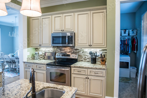 A small appliance microwave in a green kitchen with cream colored cabinets in a new construction home with granite countertops and lots of cabinets and storage space