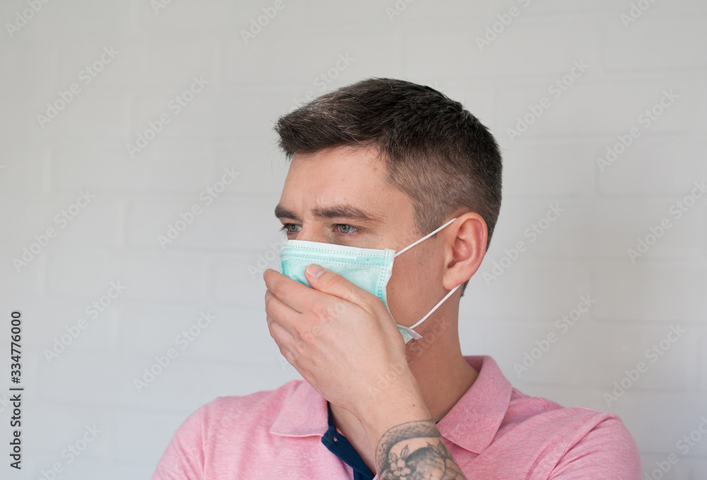 Portrait of dark hair european man in surgery face mask in pink polo on white bricks background Portrait of dark hair european man in surgery face mask in pink polo on white bricks background