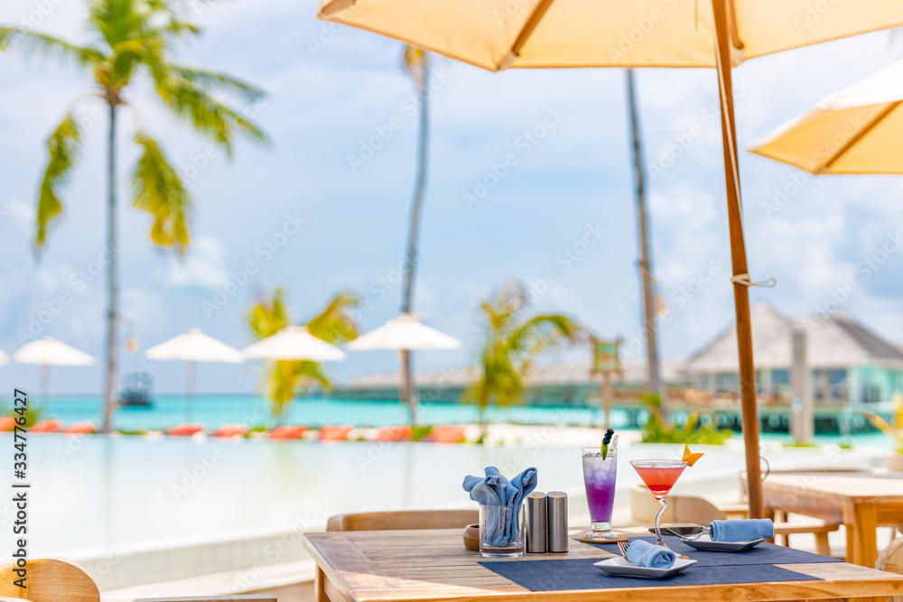 Luxury travel and vacation scenery, infinity pool, palm trees and umbrella with table mango smoothie and watermelon smoothie on table with swimming pool and sea beach background