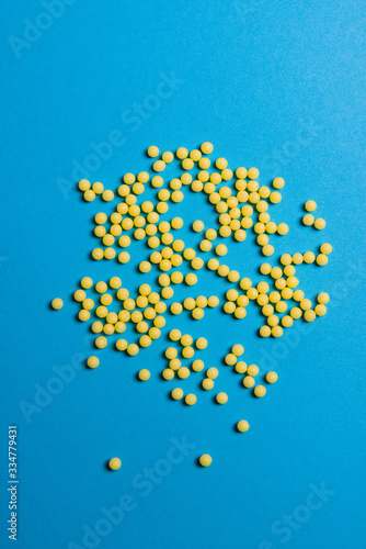 Yellow medical pills on blue background with copy space for text. Alternative homeopathy medicine  healthcare and wellness concept.