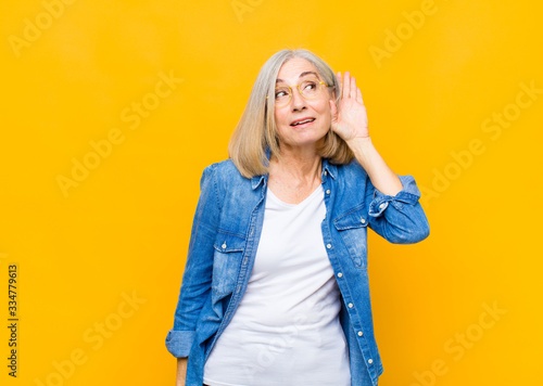 Foto senior or middle age pretty woman smiling, looking curiously to the side, trying
