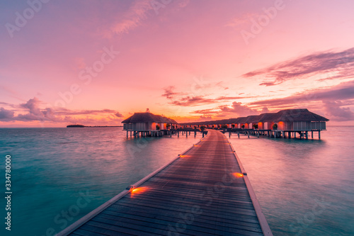 Amazing sunset landscape. Picturesque summer sunset in Maldives. Luxury resort villas seascape with soft led lights under colorful sky. Dream sunset over tropical sea  fantastic nature scenery