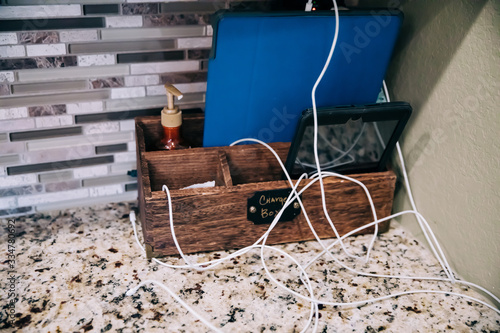 messy electronics charging station with many tangled cords charging a cell phone and tablets photo