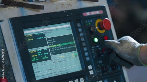 Factory worker is programming a CNC milling machine. Metalworking milling machine. Produces metal detail in a factory. A metal workpiece is machined by an electric machine.