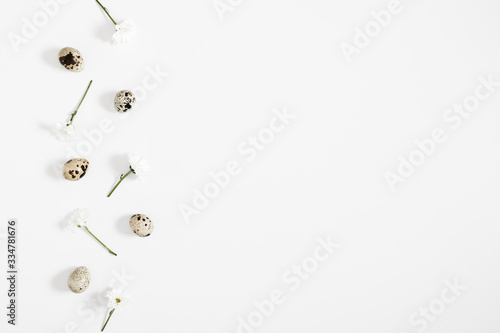 Easter creative composition. Quail eggs and white flowers on white background. Natural easter concept, pattern. Flat lay, top view, copy space 