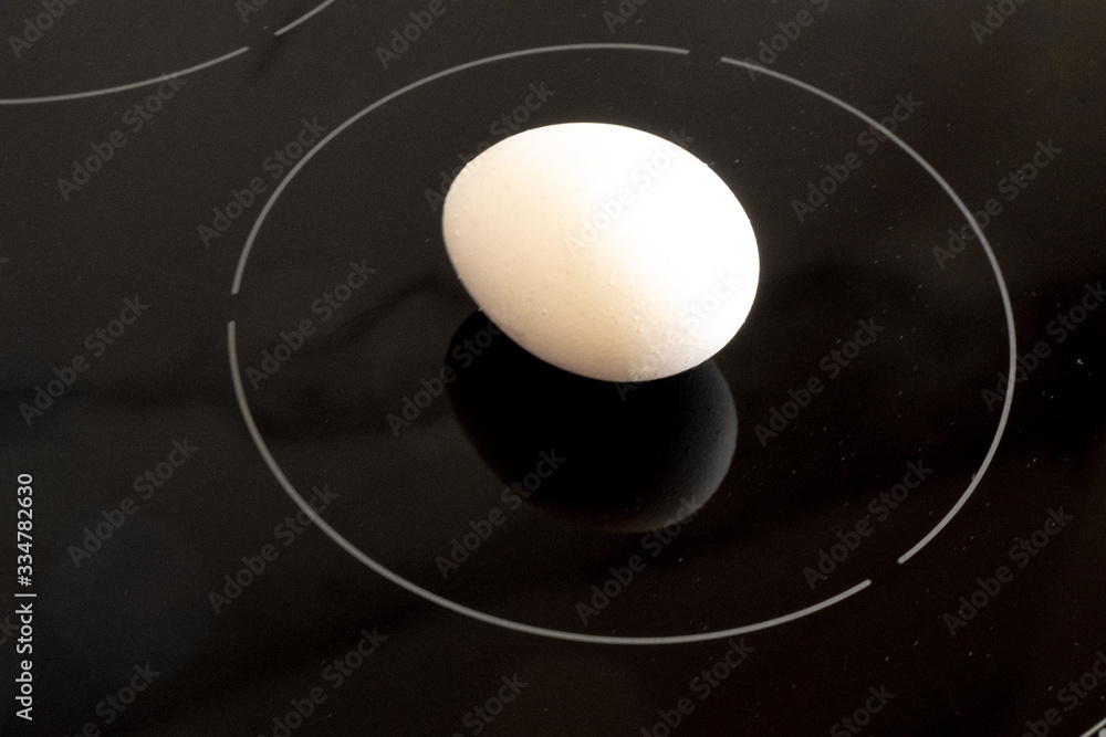 Fototapeta premium Minimalistic futuristic white chicken egg on black cooktop