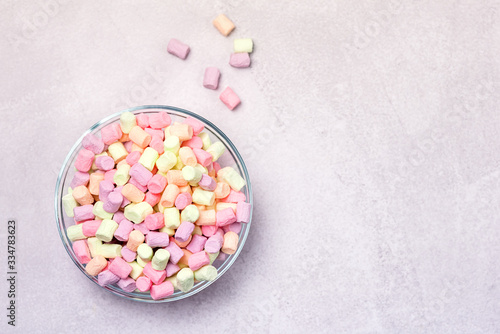 Glass Bowl with Colorful Miniature Marshmallows on Gray Background Top View Copy Space