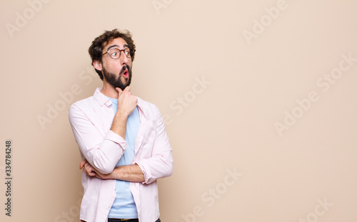 young bearded man expressing a concept against flat wall