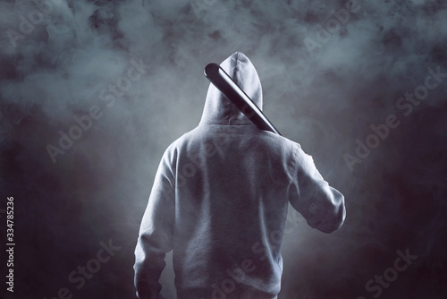 Photos Mann mit Kapuzenpullover und Baseballschläger in der Dunkelheit