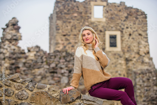 Totally happy. autumn vacation to ancient city. Travel destinations. Woman makeup on stony ruins. Explore midcentury castle ruins. feeling cosy and sporty. girl in sweater. Fashionable girl tourist