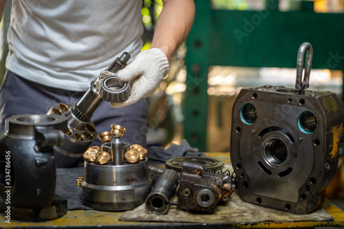 Professional mechanic man holding bearing of the hydraulic piston pump to inspection and repair maintenance heavy machinery