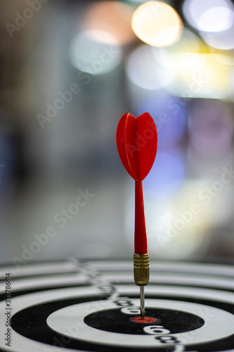 Close up shot red dart arrow on center of dartboard