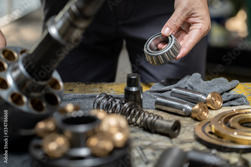 Professional mechanic man holding bearing of the hydraulic piston pump to inspection and repair maintenance heavy machinery