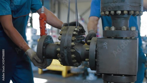Oil and Gas Wellhead tree equipment production plant. Worker assembles of wellhead fitting. Modern tendencies of machine engineering. Equipment for wellhead conncetion of oil and gas wells.