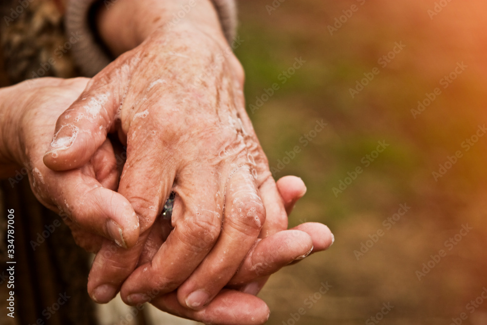 Hands of an old grandmother in a mile close-up. Grandmother disinfects her hands with soap due to an outbreak of coronavirus and a large number of infected Hands of an old grandmother in a mile close-up. Grandmother disinfects her hands with soap due to an outbreak of coronavirus and a large number of infected