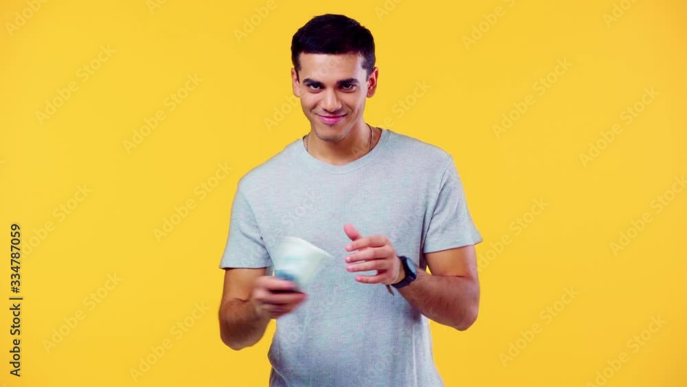 happy man counting money and smiling at camera isolated on yellow happy man counting money and smiling at camera isolated on yellow