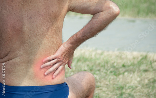 elderly person holding hand for an inflamed place on the lower back,
