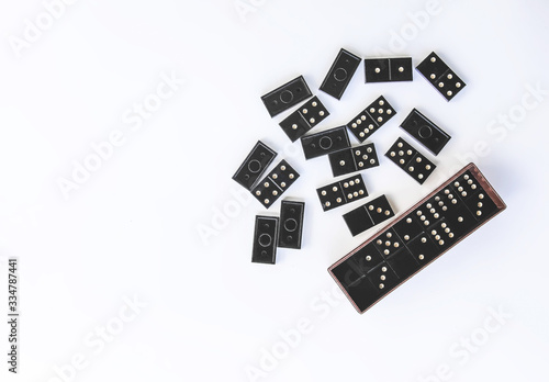 Heap of vintage black domino tiles and dominoes in the box on light background