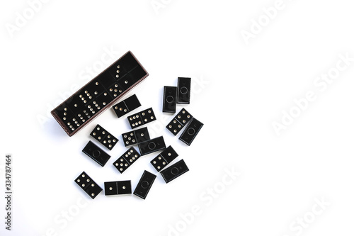 Heap of vintage black domino tiles and dominoes in the box on light background